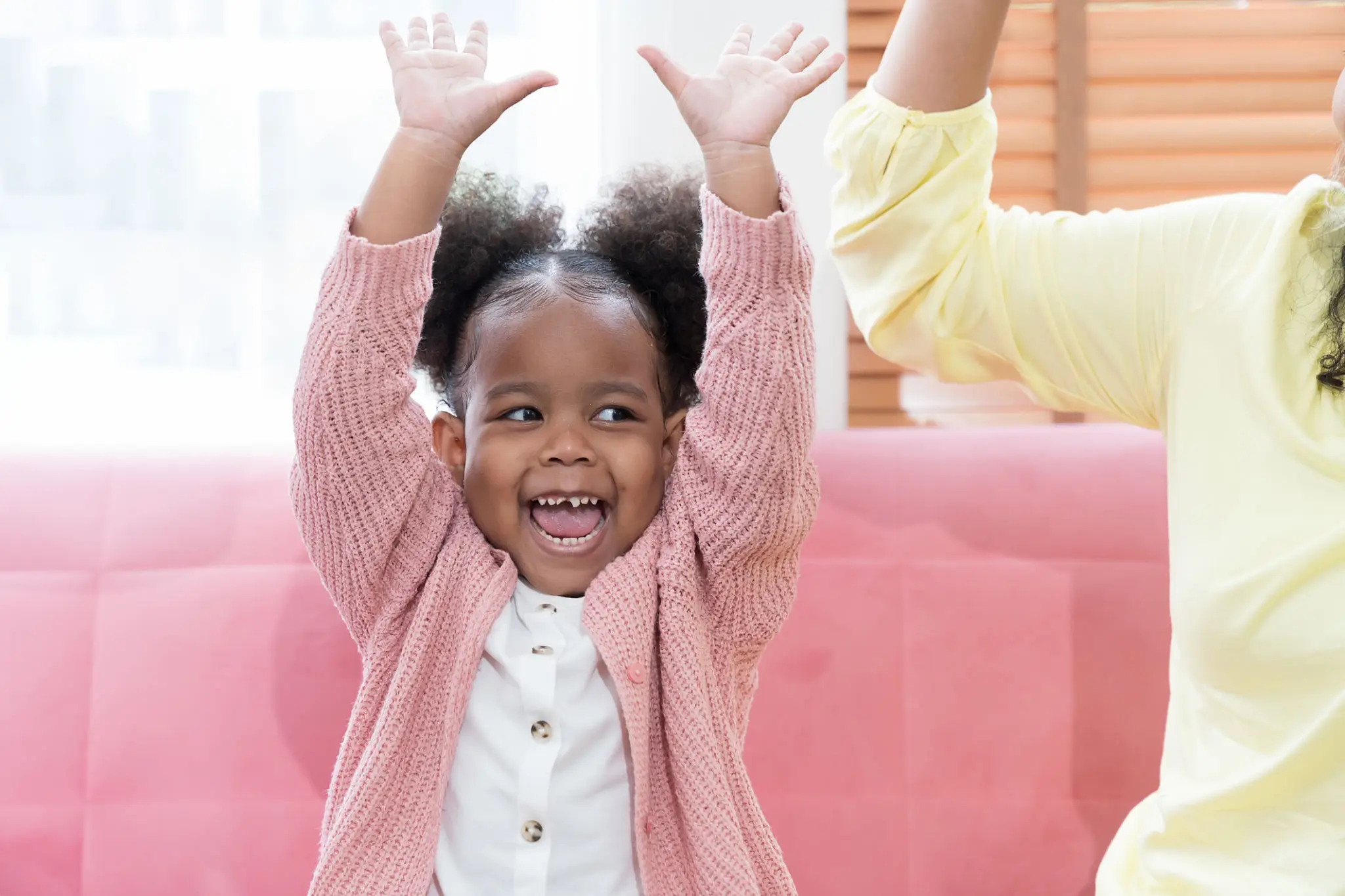 A joyful girl raising her hands with a big smile.