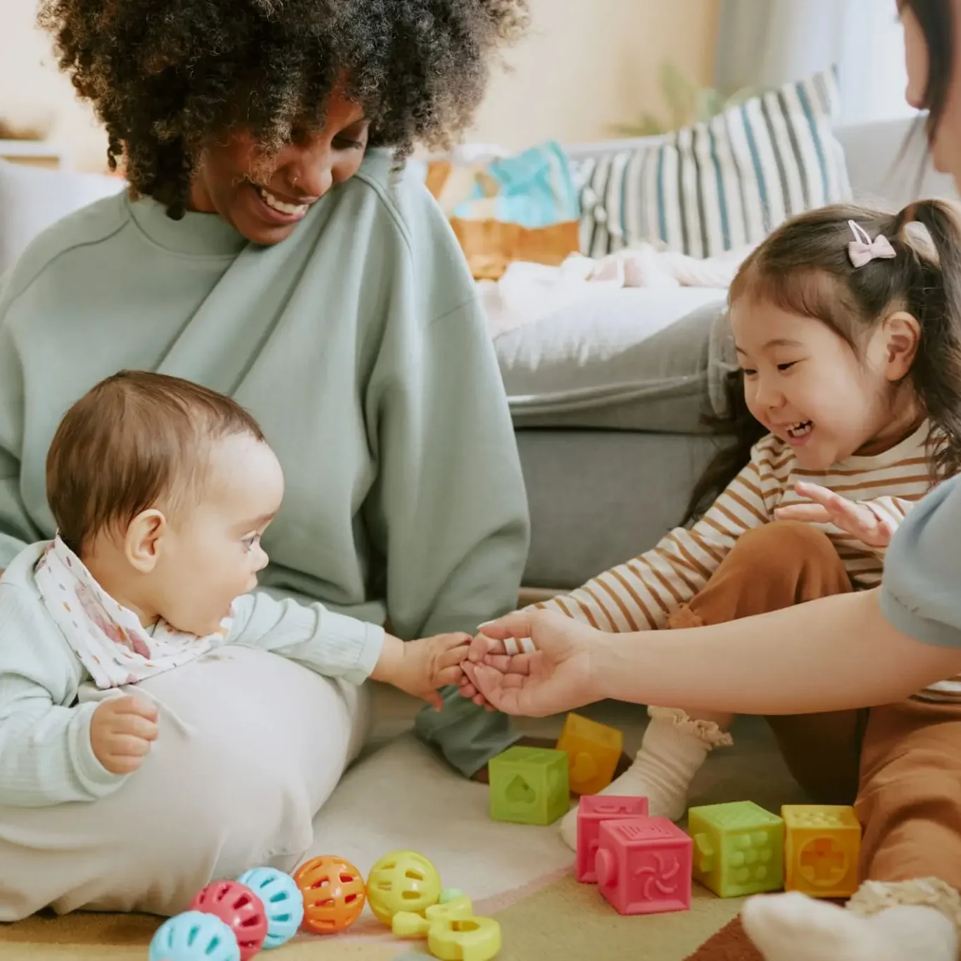 Two children playing with toys while adults watch.